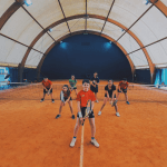 Gruppo persone gioca a tennis al coperto.