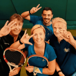 Gruppo sorridente di tennisti con racchette.